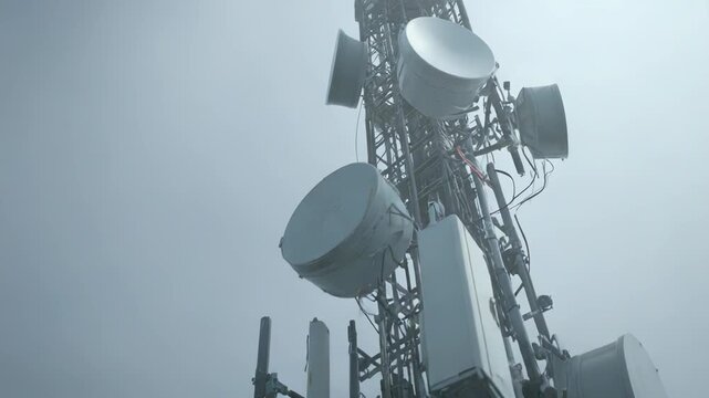 Communication tower bristling with antennas and microwave dishes, extending cellular, satellite and wireless data coverage across a clear sky for modern telecommunication networks