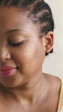 Vertical video: Camera revealing woman tilting head down then up at home, content, yellow top