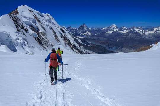 Mountaineers in rope team with crampons descending on glacier Grenzgletscher and mountain panorama with summits Lyskamm, Matterhorn and Dent Blance (left to right) in Pennine Alps, Switzerland