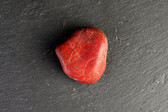 Smooth red jasper stone with natural lines on dark slate background