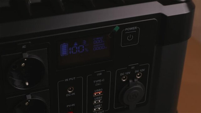Turning on portable power station with digital LCD display showing battery status