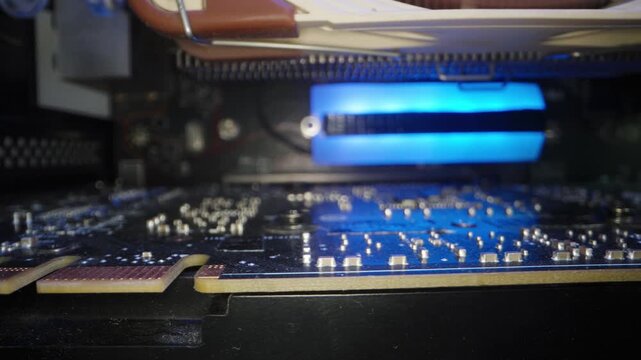 Microelectronic components in a desktop computer, rainbow RGB lighting on the NVMe drive's heatsink. Dolly slider, close up.