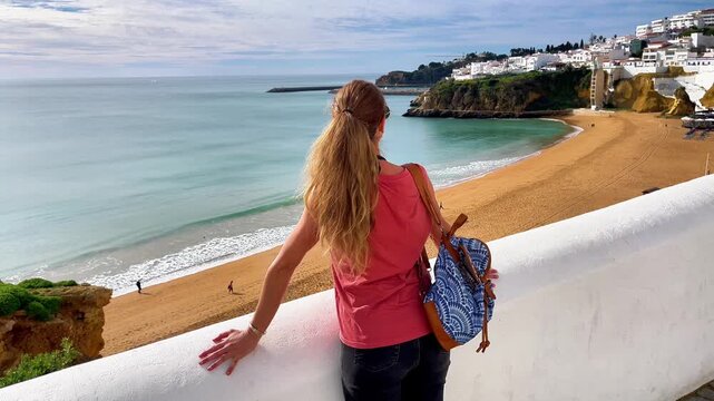 Back view of a woman tourist looking at Praia dos Pescadores beach in Albufeira, Algarve, Portugal.