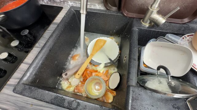 Clogged kitchen sink filled with food waste and dirty dishes.