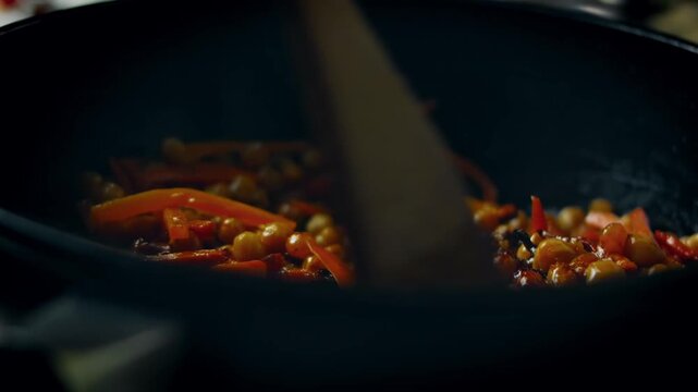 Vegetables frying with chickpeas in cauldron for wedding pilaf, close up