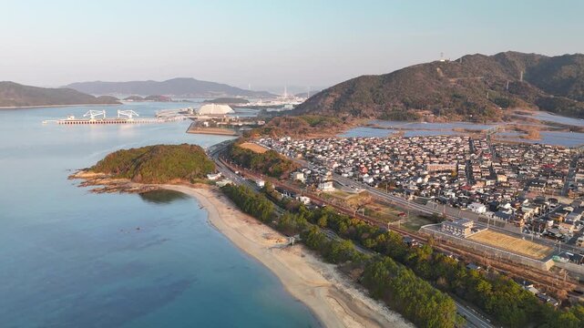 Aerial drone view of cars driving along a coastal road by the blue sea in Japan 01