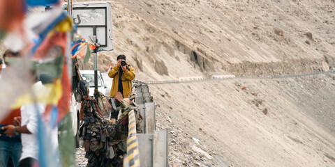 Naklejka premium Man in brown jacket stands with eyes closed and hands on chest, feeling peaceful in serene landscape of leh ladakh india, popular travel destination for tourist seeking himalayan adventure