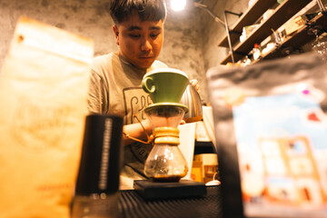 Young Asian man barista manual coffee brewing pour over method specialty coffee shop warm ambient...