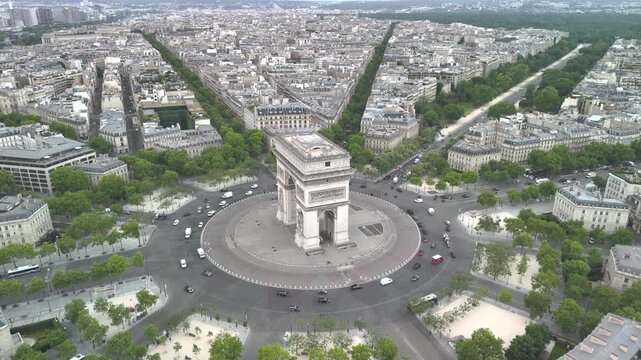 Aerial view of the famous landmark Triumphal Arch or Arc de Triomphe and Eiffel Tower surrounded by busy streets and lush greenery in the heart of the city Paris, France. Aerial drone orbiting flight