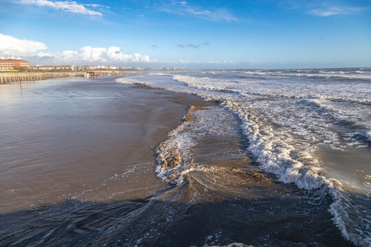 Serene low season at Evrenseki beach with golden sunset light illuminating white foamy surf. Deserted sandy coastline stretching into distance under soft evening sun. Side, Antalya, Turkey.