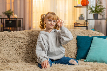 Young teenager girl putting on glasses with thoughtful and focused expression at home. Caucasian...