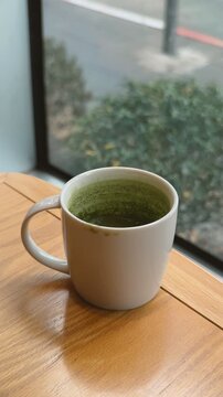 Cup of drink green tea on wooden table in the cafe.