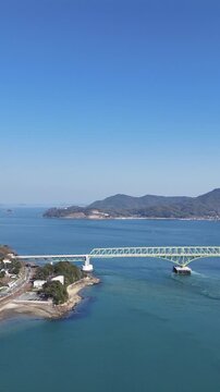 Vertical aerial drone view of cars crossing a bridge over the Seto Inland Sea with ships in Japan 02