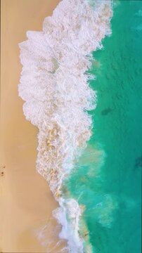 Aerial drone footage of big waves crashing on a sandy tropical beach. Vertical fullHD video. Top view of powerful ocean surf and blue sea water. Perfect for mobile content, travel background.