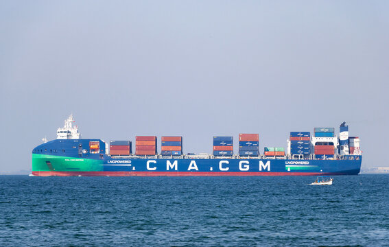 Large LNG powered CMA CGM container ship transporting colorful cargo boxes on the blue sea with a small fishing boat nearby, İzmir Bay, İzmir, Turkey. March 11, 2026.