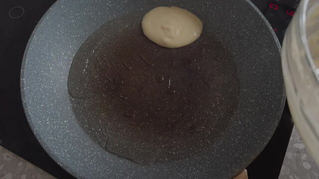 Fresh gluten-free pancake batter pouring with ladle into a hot frying pan.