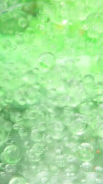Vertical video. Green Bubbles Underwater, Macro Abstraction. Concept Of Adding Something To Water.