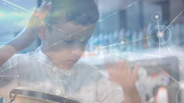 Vertical video: Leaning child in shirt gesturing over box at desk, starting node haze for learning