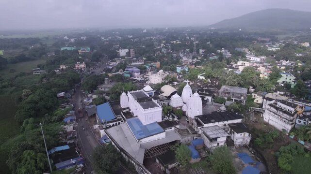 Wide aerial drone shot of Chhatia Bata Jagannath Temple surrounded by greenery in Odisha, India.