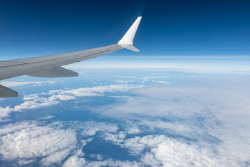 Obraz premium Airplane wings extend above white clouds, providing clear view of atmospheric layers and sense of altitude during the flight, air transportation