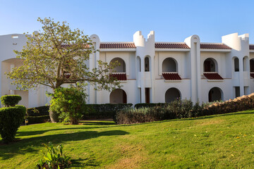 A white hotel building Arabian resort with green planted grounds.