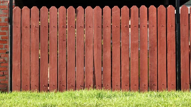 Red wooden picket fence creating a boundary with green grass yard