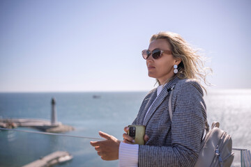 Fototapeta premium Businesswoman blonde sunglasses seaside view contemplating ocean success on sunny day copy space