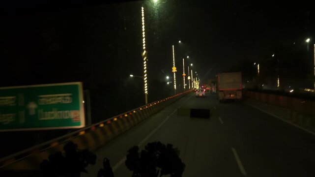 Night traffic on busy urban road with cars, buses and street lights, long queue of vehicles under dark sky, transportation and travel scene showing motion, infrastructure evening city life in India