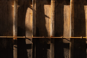 Fototapeta premium Wooden wall with strong shadow silhouette and warm sunlight, abstract cinematic background with copy space