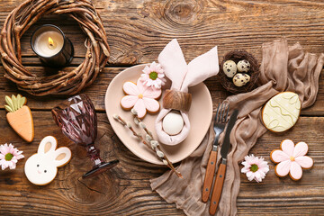 Beautiful table setting with different Easter cookies, eggs, burning candle and pussy willow branches on wooden background © Pixel-Shot