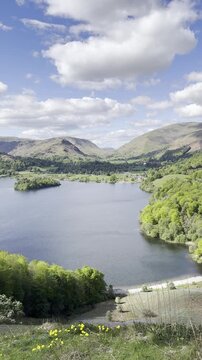 Panoramic view of Grasmere Lake, surrounding hills and Rydal Water under a blue sky with scattered clouds, seen from a high hillside. Lake District, England, UK.