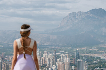 Woman in sportswear overlooking urban skyline and mountain landscape