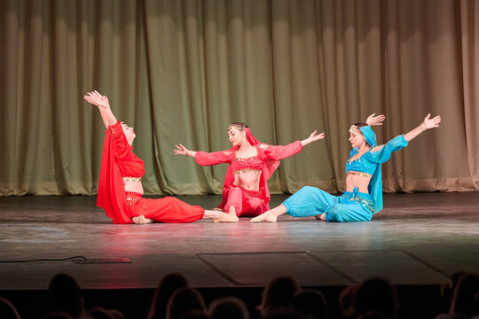 Three odalisques in vibrant costumes performing traditional dance on stage