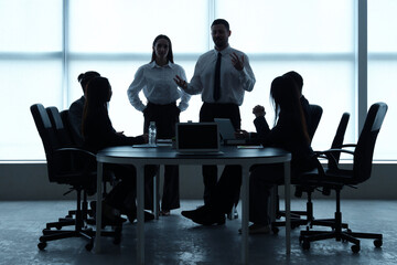 Silhouettes of business people working at table in office
