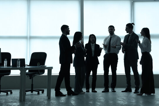 Silhouettes of business people talking in office