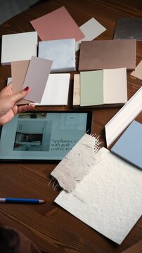Client choosing paint color for interior renovation of home with color shade cards, fabric samples in designer's office