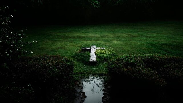 White cross placed beside a narrow stream cutting through lush cemetery lawn at dusk conveying serene solitude faith remembrance and peaceful eternal rest