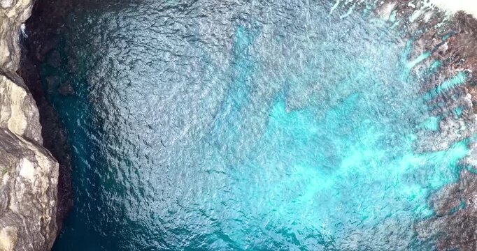Top-down drone view of Broken Beach (Pasih Uug), Nusa Penida, Bali, revealing the unique circular limestone cove filled with turquoise water and surrounded by rugged cliffs and greenery.