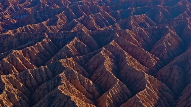 Aerial view captures stunning Ak-Say canyons along Issyk-Kul lake. Eroded landscape showcases unique geological formations during golden hour.