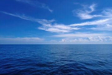 Fototapeta premium Wide blue ocean horizon wispy clouds and calm deep water under a bright clear sky