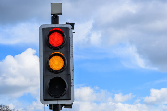 Red and amber traffic light against blue sky UK road signal