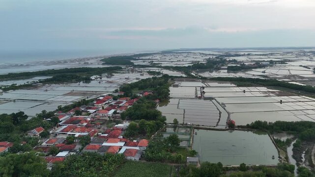 Aerial View of Flooded Coastal Village and Salt Pond Under Overcast Sky.