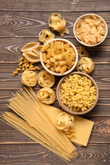 Fototapeta premium Bowls with different types of pasta on wooden background