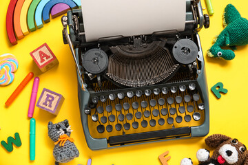 Obraz premium Composition with vintage typewriter and knitted toys on yellow background