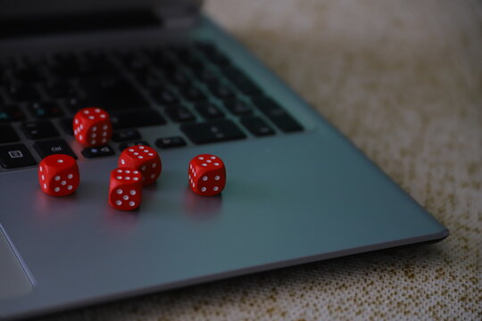Red Dice Scattered on Dark Laptop in Moody Low-Light Setting