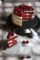 Tasty cherry cake and board with piece on grey tile table
