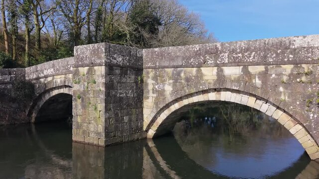 Reflections Of Ponte Romana de Brandomil (Brandomil Roman Bridge) Over Xallas River In Zas, Spain. Aerial Sideways Shot
