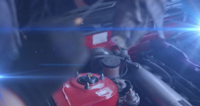 Gloved technician grabbing cloth and wiping red strut tower for service in auto shop showing grime