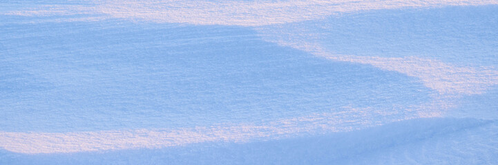 Beautiful winter background with snowy ground. Natural snow texture. Wind sculpted patterns on snow surface. Wide panoramic texture for background and design. © Andrei Stepanov