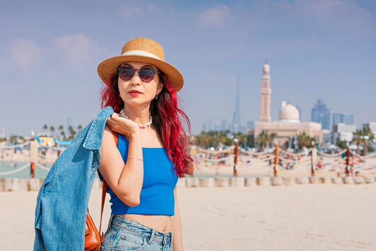 Young woman exploring Dubai's urban beach, enjoying travel and leisure under the clear conditions with the cityscape visible